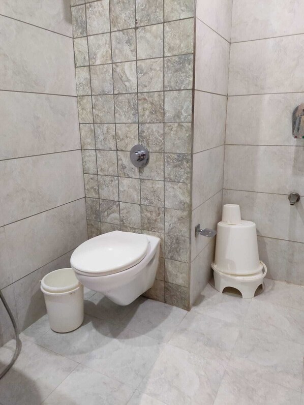 A bathroom with a toilet, a trash bin, and a bidet. - Hotel Luxura (Sidhpur)