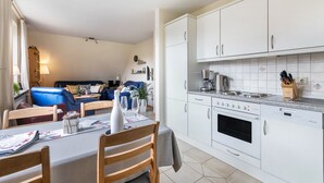 Una cocina moderna con armarios blancos, horno empotrado y encimera con cafetera.