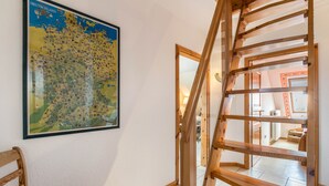 Una escalera con barandillas de madera, un mapa en la pared y una silla.