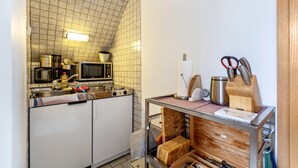 Eine kompakte Küche mit Mikrowelle, Spüle und einem Schneidebrett auf einem Gestell.