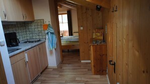 Una cocina pequeña con cafetera, armarios de madera y salpicadero de azulejos.
