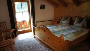 Un dormitorio con estructura de madera, una cama, sillas y una ventana.