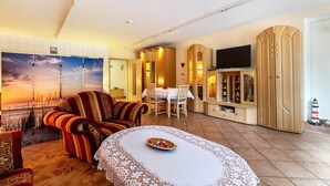 A living room with a sofa, a dining table, a TV, and a cabinet. - Apartment 'Ferienwohnung 'ole Bäckerie'' with Shared Terrace, Private Garden and Wi-Fi (Delve)