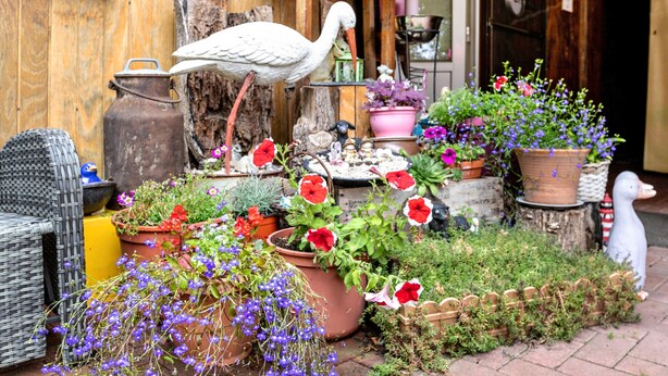 A garden with potted plants, a white bird sculpture, and a rustic wooden structure. - Apartment 'Ferienwohnung 'ole Bäckerie'' with Shared Terrace, Private Garden and Wi-Fi (Delve)