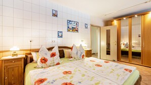 A hotel room with a bed, wooden nightstands, a wardrobe, and a tiled wall with nautical-themed decorations. - Apartment 'Ferienwohnung 'ole Bäckerie'' with Shared Terrace, Private Garden and Wi-Fi (Delve)