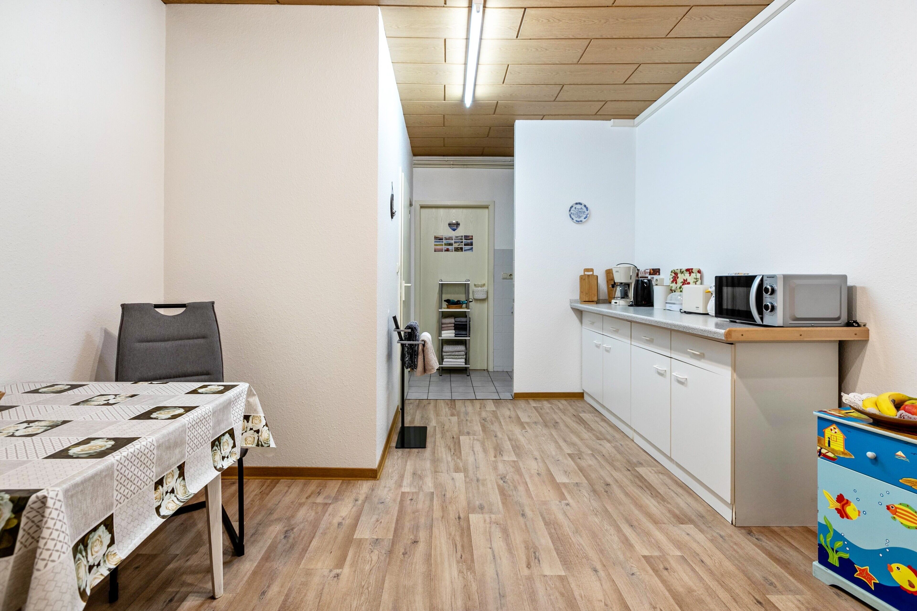 Une cuisine compacte comprenant une table à manger, un four à micro-ondes et un meuble aux couleurs vives.