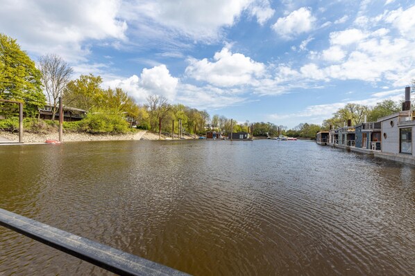 A river with buildings on both sides, a wooden dock, and a clear sky.