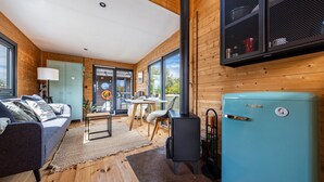 Ein modernes Interieur einer Blockhütte mit einer Couch, einem Tisch, Stühlen, einem blauen Kühlschrank und einem Kamin.