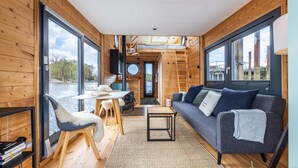 Ein Ferienhaus-Interieur mit Essbereich, einer Couch und großen Fenstern.