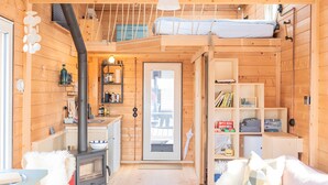 A compact wooden cabin with a kitchenette, a bed with a loft, and a door leading to an outdoor area. - Holiday Home 'Besonderes Tiny Hausboot Marianne' with Private Terrace and Wi-Fi (Hamburg)