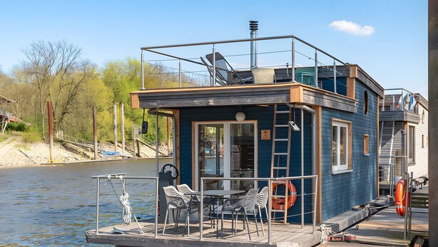 A houseboat with a deck, a table, chairs, and a lifebuoy. - Holiday Home 'Besonderes Tiny Hausboot Marianne' with Private Terrace and Wi-Fi (Hamburg)