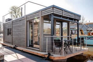 A floating houseboat with a deck, outdoor seating, and a view of the water. - Holiday Home 'Dein Hausboot Wilma In Hamburg' with Private Terrace and Wi-Fi (Hamburg)