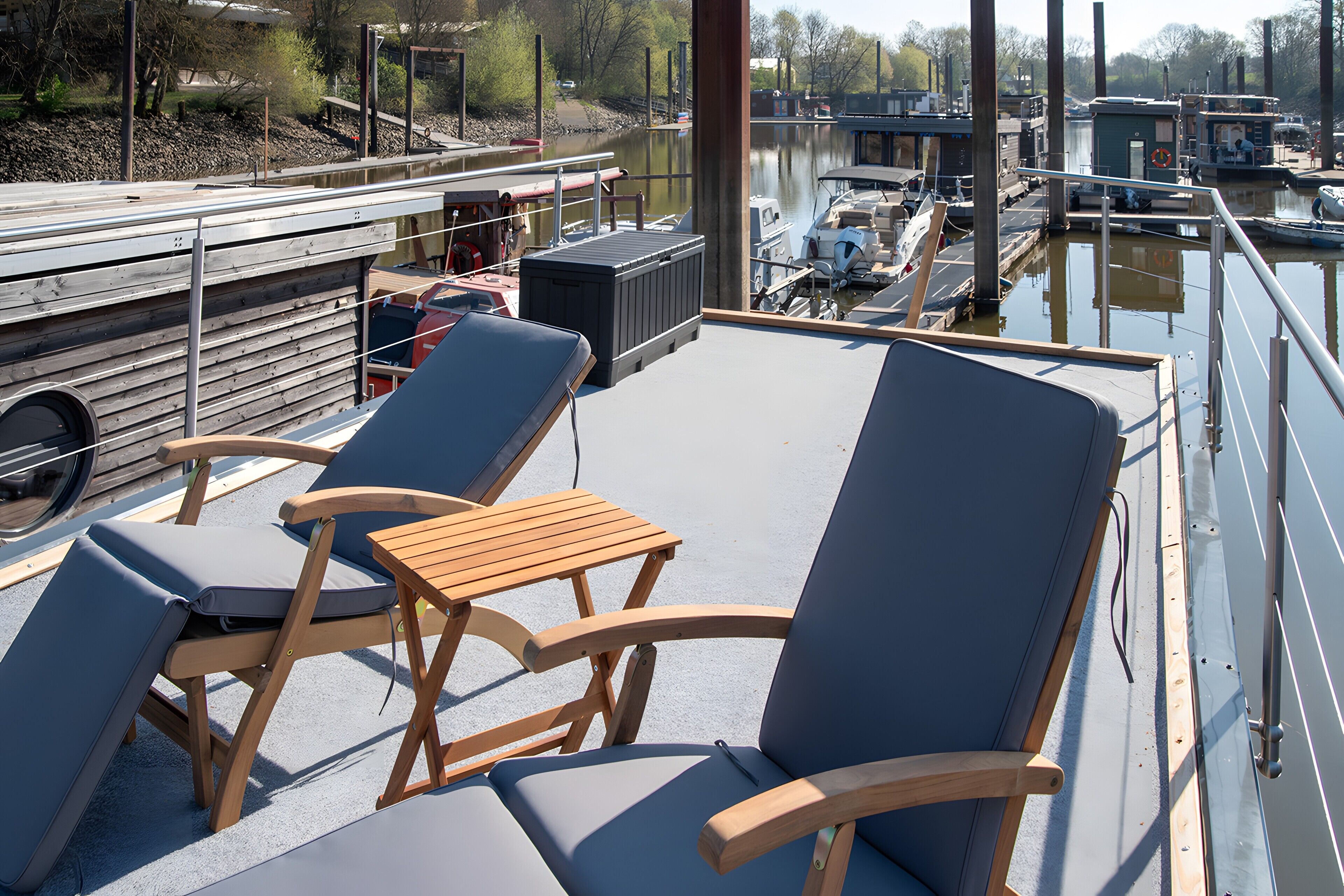 Una terrazza con poltrone da relax e un tavolo, con vista su una superficie d'acqua tranquilla e barche.