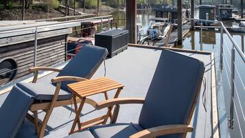 Una terrazza con poltrone da relax e un tavolo, con vista su una superficie d'acqua tranquilla e barche.