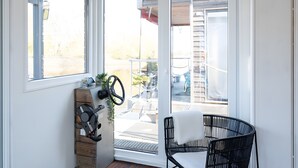Une pièce avec une grande porte-fenêtre coulissante, une chaise noire, un volant et une petite plante.