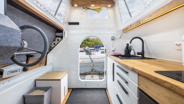 A compact kitchen with a wooden countertop, a sink, and a window with a view of boats.