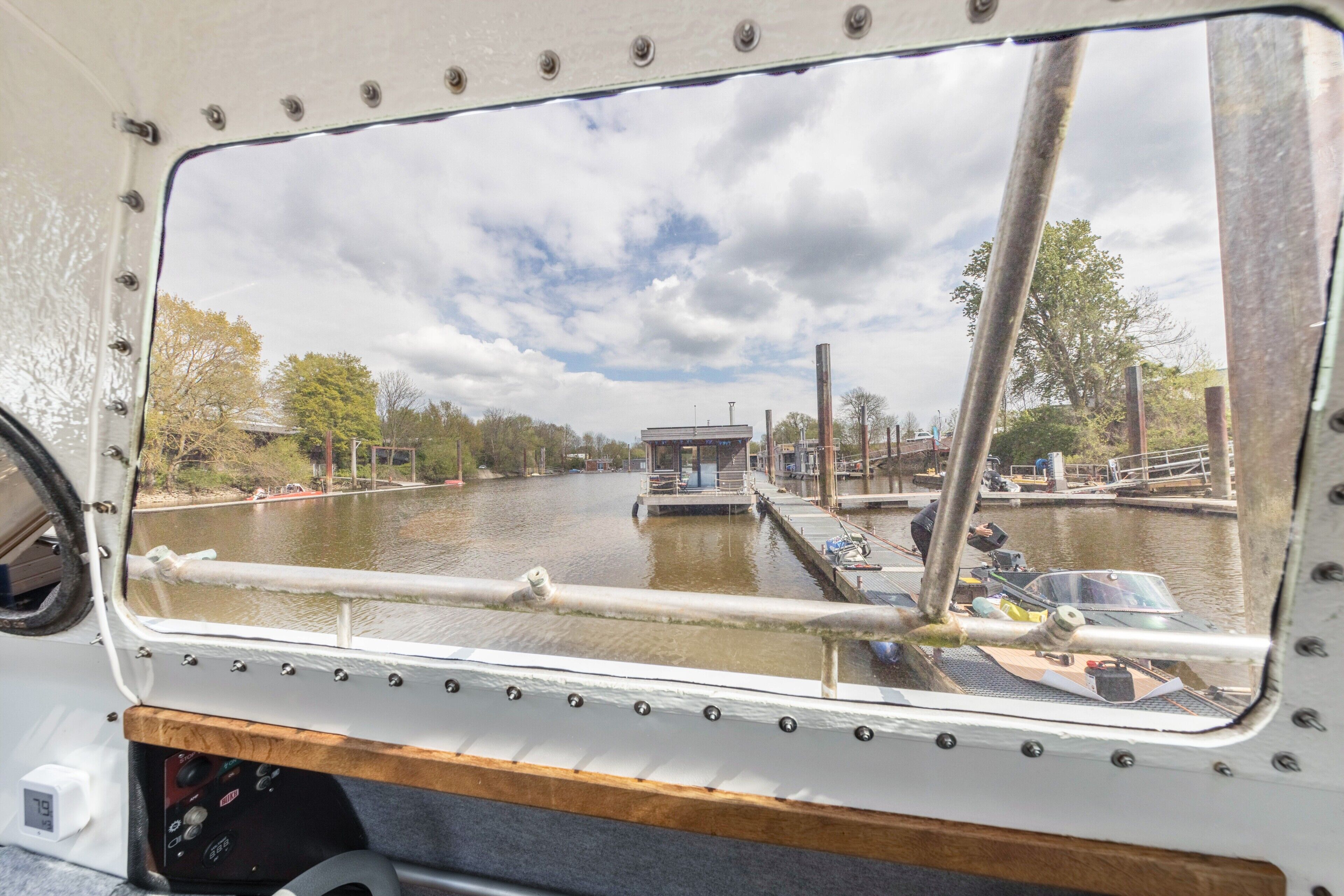 A view from a boat's window, including a lock system, a small building, and trees along the water.