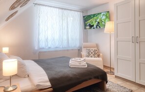 Un dormitorio con cama, televisor, lámpara y armario.