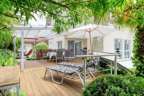 Un patio con mobiliario exterior, una parrilla y una zona de estar cubierta.
