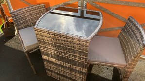 Un conjunto de mesa y sillas de mimbre en un balcón con barandilla naranja.