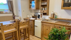 Una cocina de madera con una mesa de comedor, sillas, un refrigerador y un fregadero.