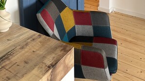 Una habitación con una puerta de estilo granero azul, una mesa de madera, un cojín colorido y una planta.