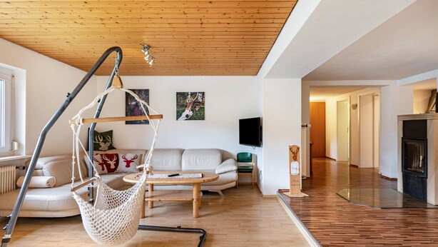 Un salón moderno con una silla colgante, sofá y televisor de pantalla plana.