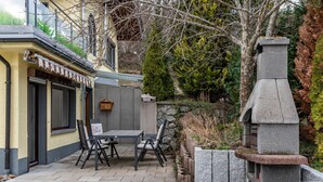 Un patio con mesa y sillas, chimenea de piedra y pared de piedra.