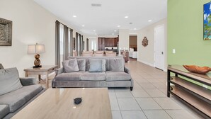 Un salon spacieux avec un canapé gris, une table basse et un coin repas comprenant une table et des chaises en bois.