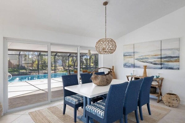 A dining area with a white table, blue chairs, a woven basket, and a hanging light fixture.
