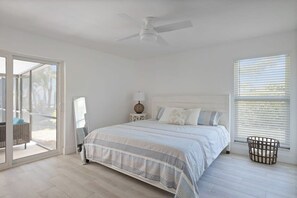 A bedroom with a bed, a ceiling fan, a nightstand, a lamp, and a window with blinds.