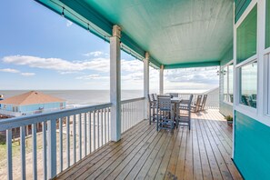 Um deck de madeira com vista para o oceano, uma mesa com cadeiras e um corrimão.