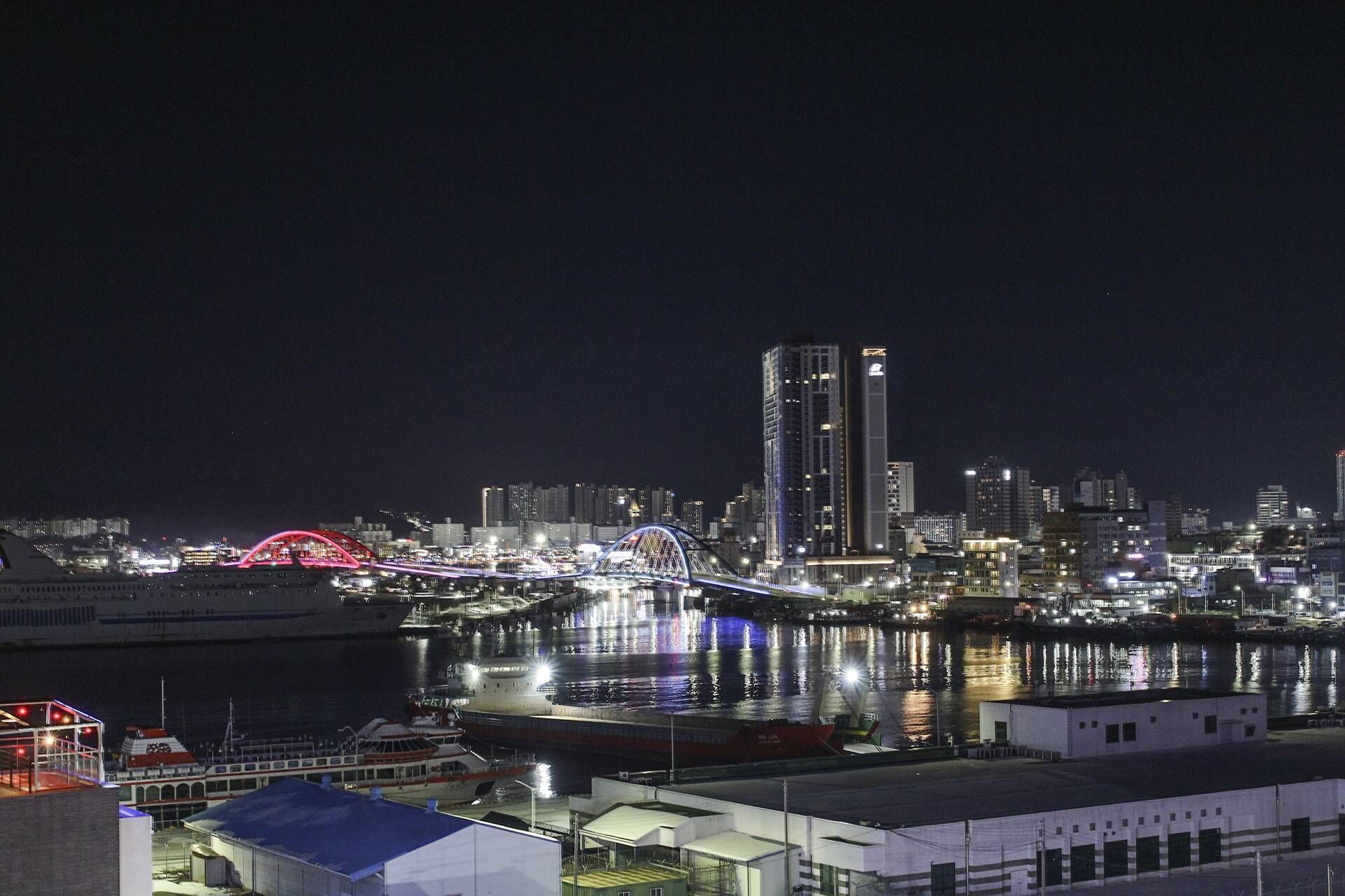A nighttime cityscape with a prominent bridge and high-rise buildings.