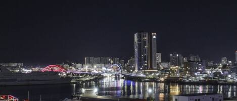 A nighttime cityscape with a prominent bridge and high-rise buildings.