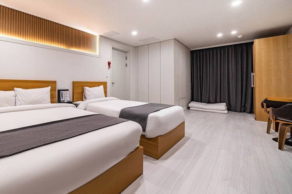 A hotel room with two beds, a desk, and a chair.