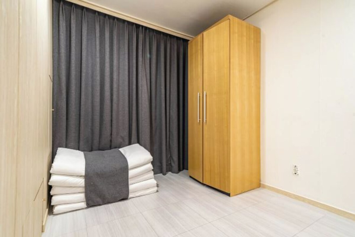 Un dormitorio con cama, armario y cortina.