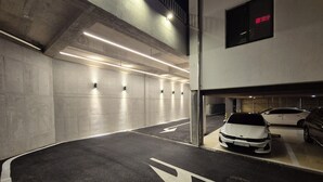 A multi-level parking garage with concrete walls, overhead lighting, and directional arrows on the floor. - RITZ HOTEL (Sokcho)