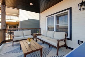 Eine überdachte Veranda mit zwei Sofas, einem Holztisch und einem Blumentopf.
