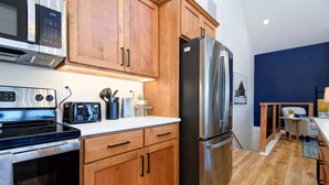 Une cuisine moderne avec des meubles en bois, un réfrigérateur en acier inoxydable, un four à micro-ondes et une cuisinière.