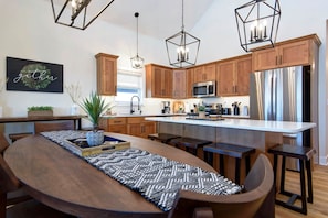 Una cocina moderna con armarios de madera, electrodomésticos de acero inoxidable y una isla central con taburetes de bar.