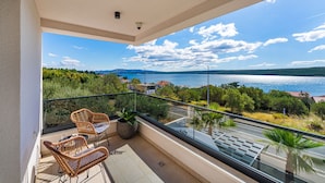 A balcony with wicker chairs and potted plants, overlooking a road and a body of water with distant hills. - Seaview villa S. with pool (Posedarje)