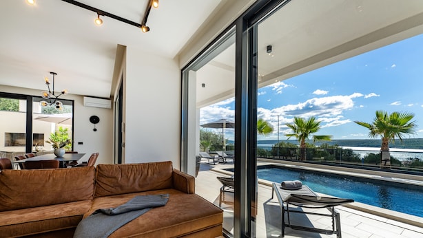 A modern living room with a large window overlooking a swimming pool and a scenic view. - Seaview villa S. with pool (Posedarje)