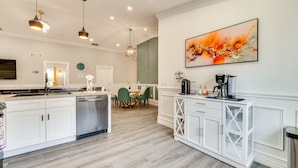 A modern kitchen with white cabinetry, a dishwasher, and a dining area with green chairs. - Heated Pool: Davenport Home w/ Xbox & Racing Games (Davenport)