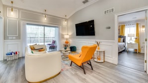 A modern living room with a sofa, armchair, and a TV mounted on the wall. - Heated Pool: Davenport Home w/ Xbox & Racing Games (Davenport)