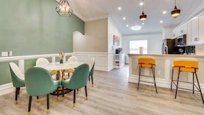 A modern kitchen with white cabinets, a central island, and bar stools. - Heated Pool: Davenport Home w/ Xbox & Racing Games (Davenport)