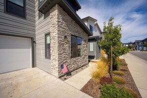 A residential building with a stone facade, a garage door, and a small flag. - Riverfront Townhome near Beach & Trails - Family & Couples Friendly (Coeur d'Alene)