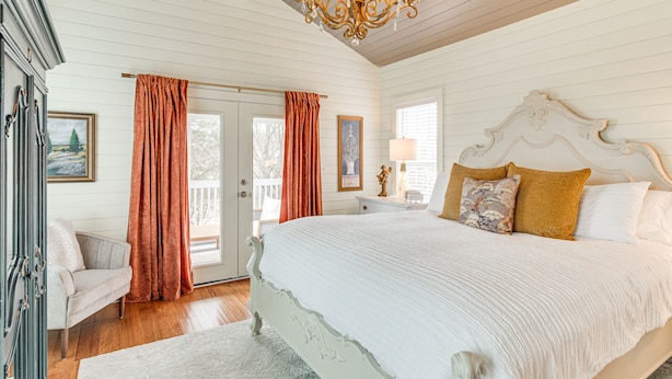 A bedroom with a large bed, a chandelier, and a view of the outdoors. - Tranquil Arrington Cottage ~ 7 Mi to Franklin! (Arrington)