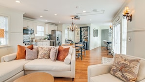 A spacious living room with a sofa and ottoman, a dining area with a chandelier, and a kitchen in the background. - Tranquil Arrington Cottage ~ 7 Mi to Franklin! (Arrington)