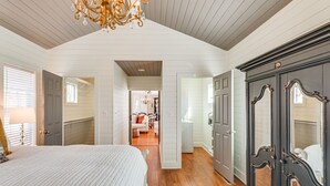 A bedroom with a large bed, wooden flooring, a dark wardrobe, and a chandelier. - Tranquil Arrington Cottage ~ 7 Mi to Franklin! (Arrington)