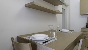 A dining table set with plates, glasses, and cutlery, with a chair and a wooden cabinet in the background. - Italianway - Martinetti 21 B (Milan)